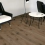 Pavimento laminato scuro Comfort Noce Tobacco posato con mobili in una scena di soggiorno.
