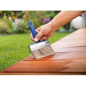 Pennello per impregnante LUX 100 mm in uso: mano che impregna terrazza in legno con pennello largo.