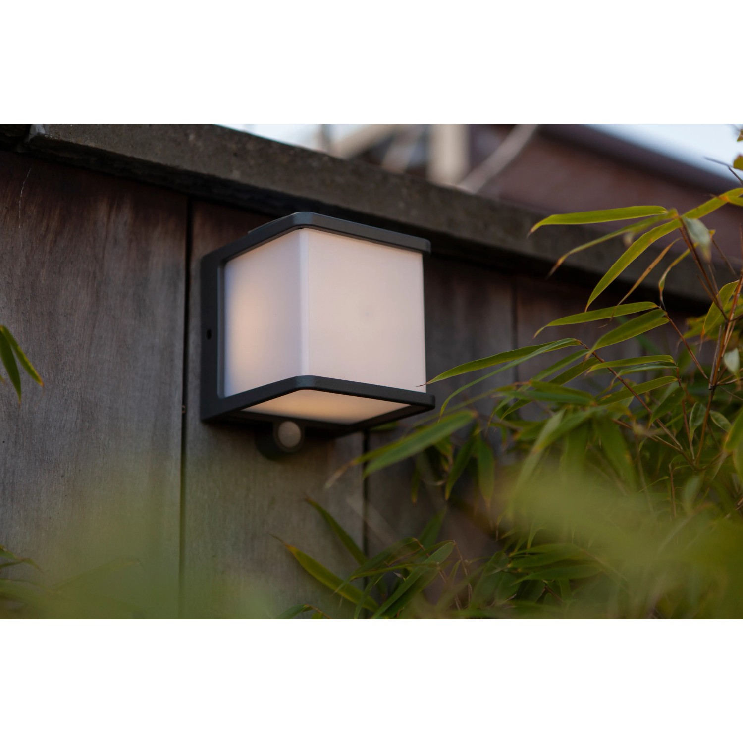 Lampada da parete solare a LED Lutec Doblo color antracite con sensore di movimento su parete di legno.