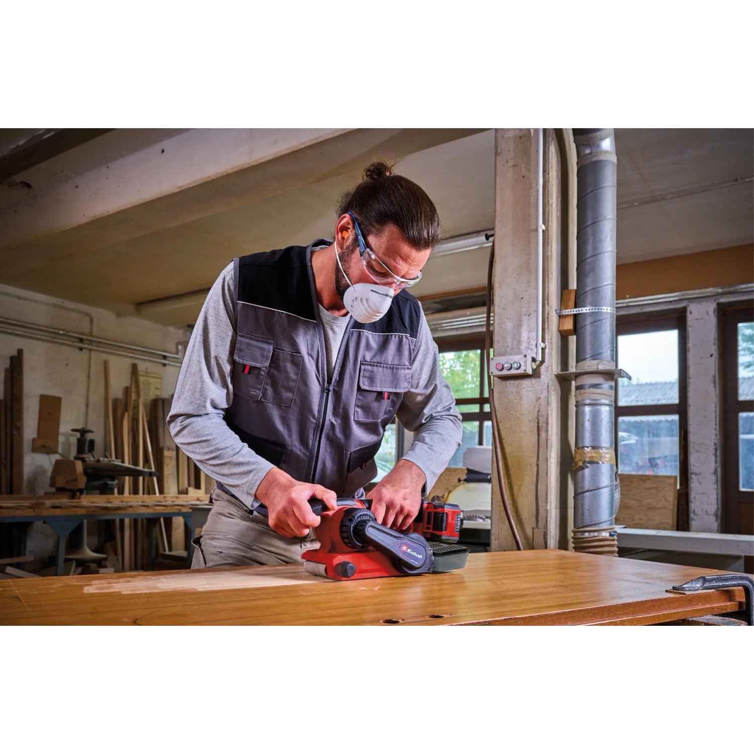 Levigatrice a nastro a batteria Einhell TP-BS 18/457 Li BL Solo mentre leviga il legno.