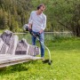 Uomo che usa il decespugliatore a benzina Al-Ko BC 223 L-S in un giardino vicino a un lago.