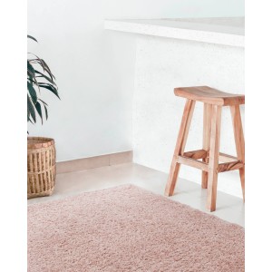Tappeto a pelo lungo rosa t.b.t. in soggiorno con sgabello in legno e pianta.