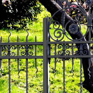 Dettaglio di una recinzione da giardino in metallo grigio decorato.
