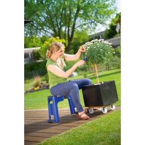 Donna seduta su sgabello da giardino LUX blu con ginocchiera, pota pianta in giardino.