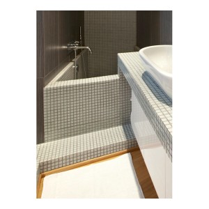 Bagno con piastrelle a mosaico su vasca e lavabo.
