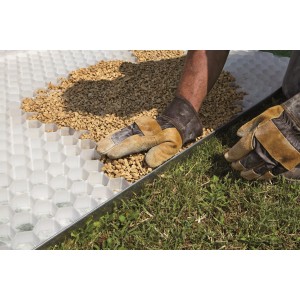 Posa di t.b.t. ciottoli e granulati in una griglia con ghiaia da parte di una persona.