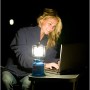 Lampada Campingaz Camping 206 L in uso: Donna usa il laptop alla luce della lampada da campeggio blu.