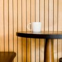 Tazza bianca su tavolo rotondo davanti a parete con pannelli di legno. Perline.