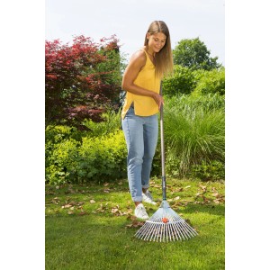 Donna che rastrella le foglie con un rastrello per foglie. Categoria: Rastrelli e scope per foglie.