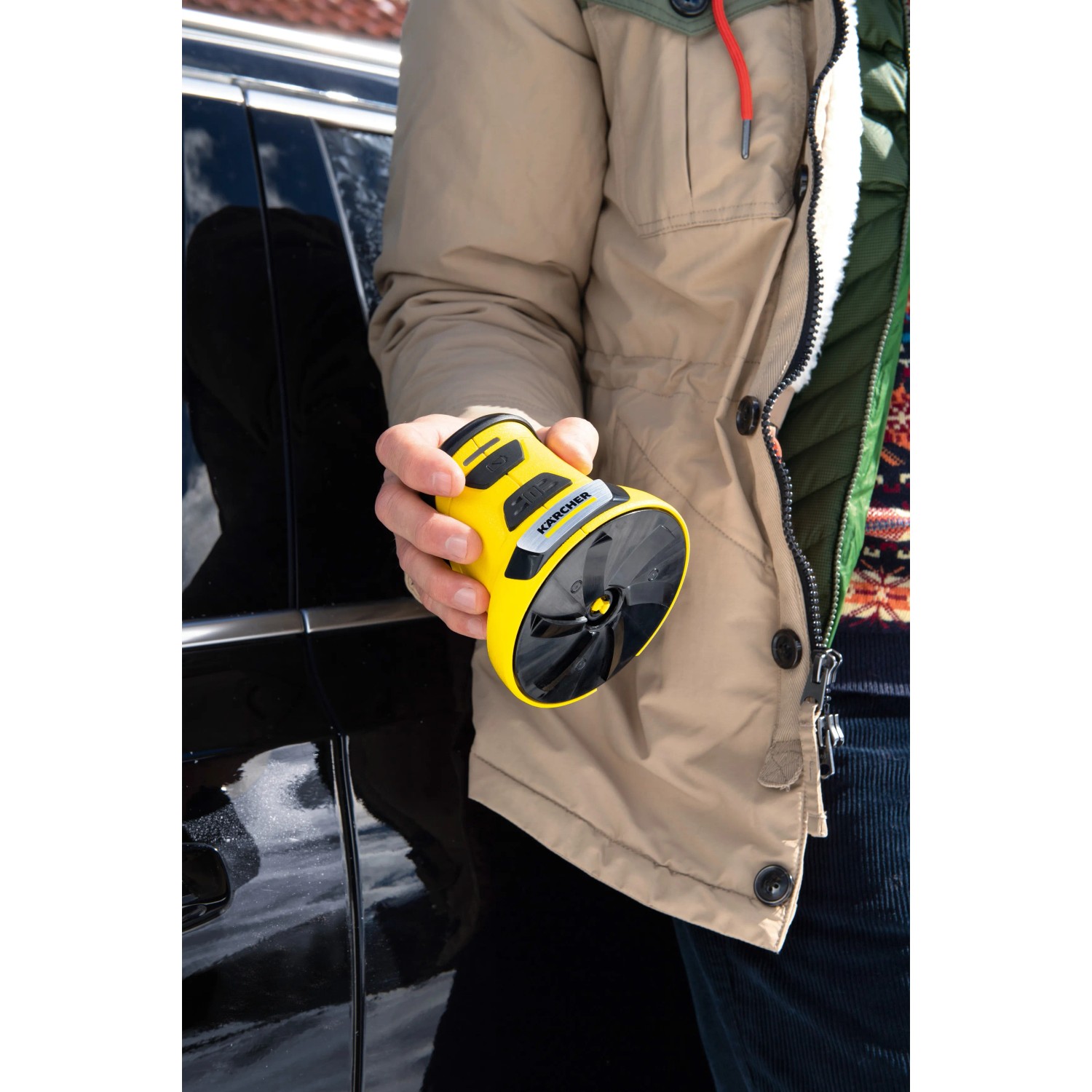 Raschiaghiaccio elettrico Kärcher EDI 4 giallo in mano davanti all'auto. Utile aiuto per l'inverno.