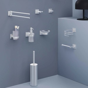 Vari accessori da bagno, come porta carta igienica, dispenser di sapone e spazzola in argento.