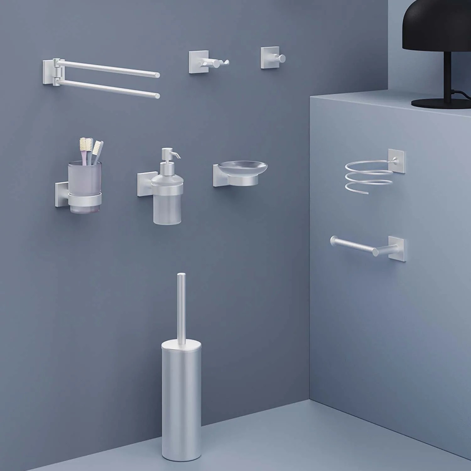 Vari accessori da bagno, come porta carta igienica, dispenser di sapone e spazzola in argento.