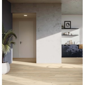 Pavimento in legno chiaro in una stanza con pianta e angolo cottura sullo sfondo.