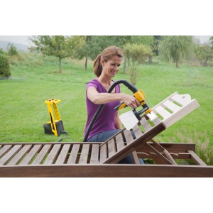 Donna che utilizza il sistema di verniciatura a spruzzo Wagner HVLP Universal W950 Flexio per spruzzare un lettino in legno in giardino.