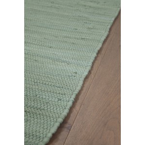 Dettaglio di un tappeto/tappeto da cucina verde chiaro su pavimento in legno.