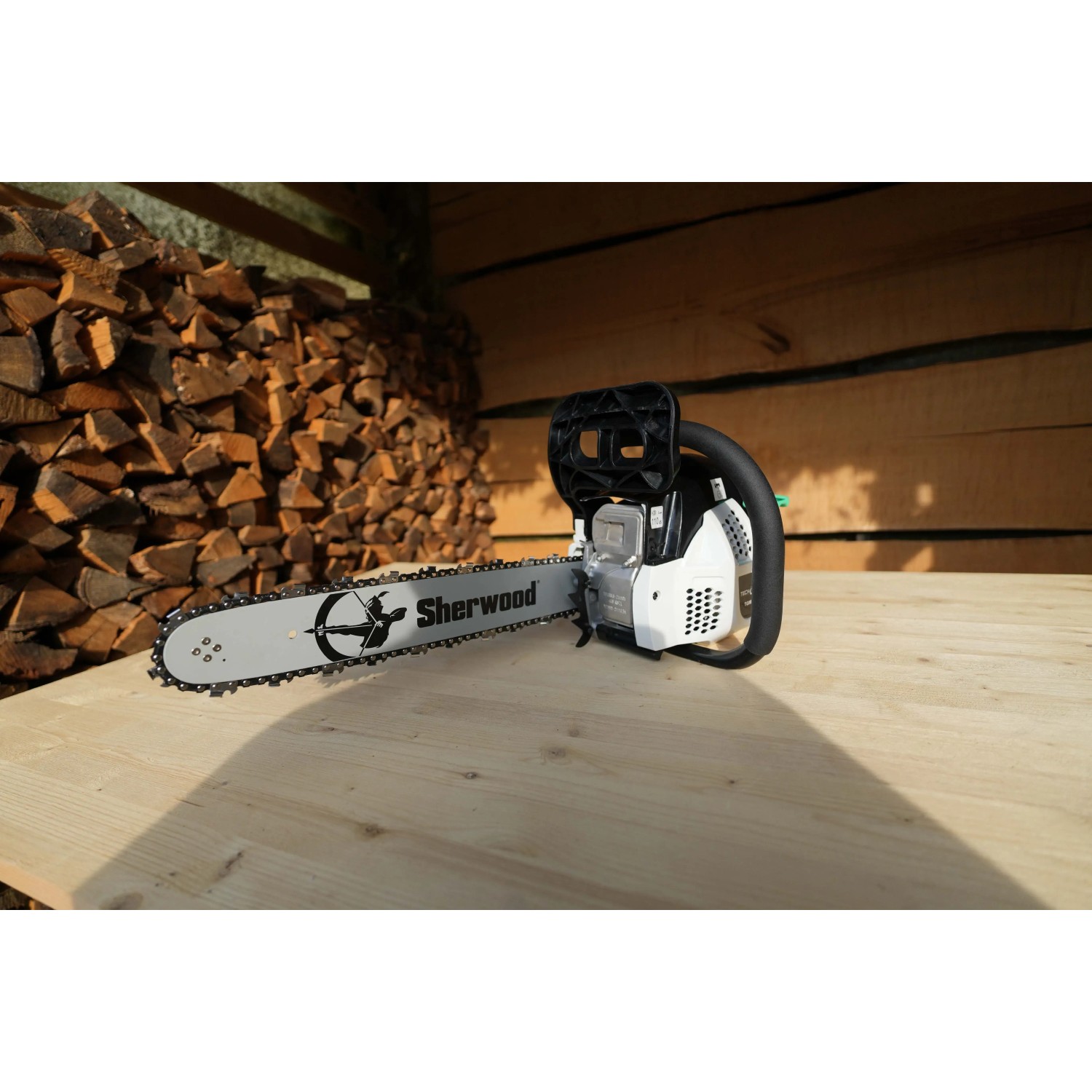 Motosega Sherwood su tavolo di legno, catasta di legna sullo sfondo.