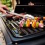 Barbecue a gas con cibo grigliato e spiedini di verdure sulla griglia.
