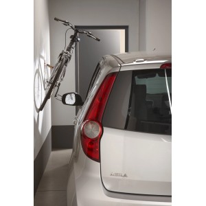 Bicicletta su supporto a parete in garage accanto all'auto. Pannelli forati per montaggio a parete.