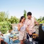 Gruppo che griglia con barbecue a gas t.b.t. in giardino. Barbecue con amici.