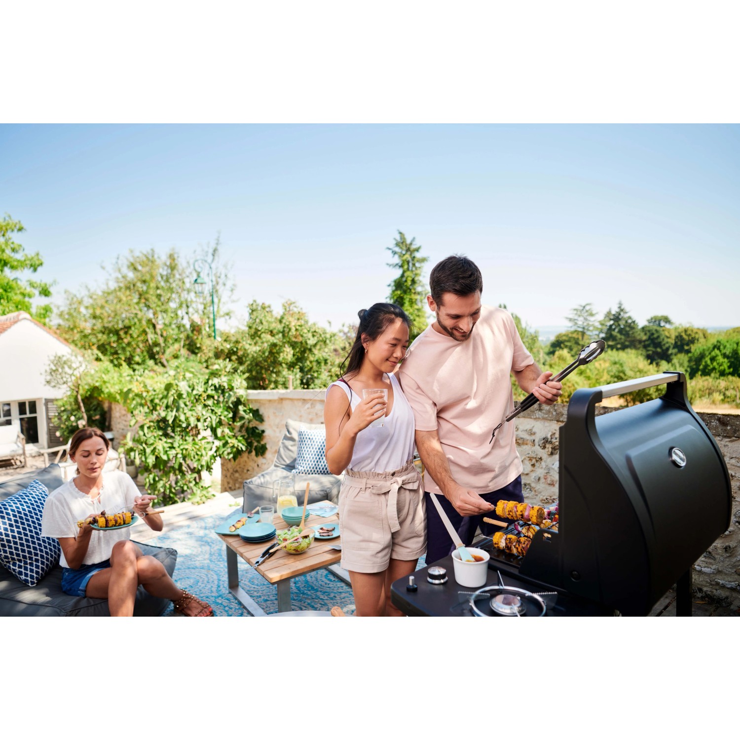 Gruppo che griglia con barbecue a gas t.b.t. in giardino. Barbecue con amici.