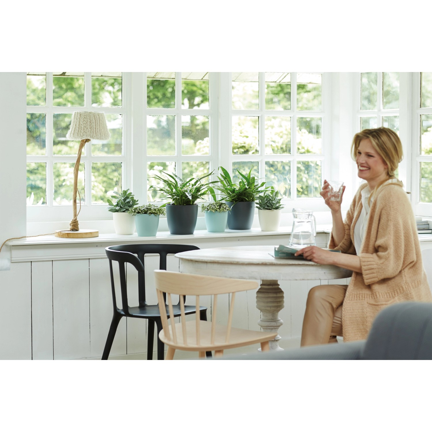 Scena con vasi Elho Brussels Round Ø 18 in vari colori su un davanzale.