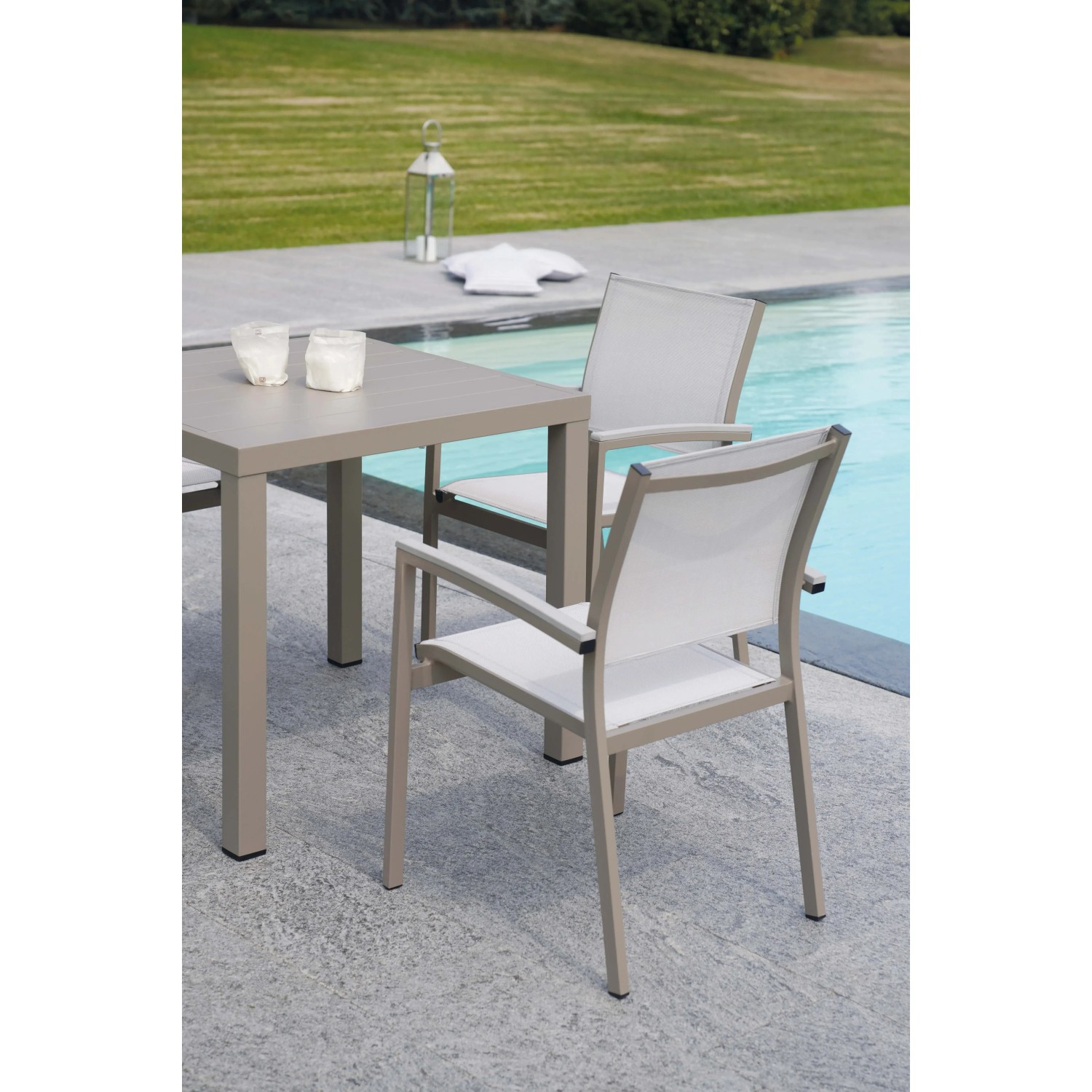 Tavolo da giardino quadrato con due sedie grigie e bianche vicino alla piscina.