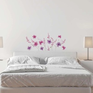 Adesivo da parete con fiori viola e rosa come decorazione murale sopra un letto.