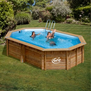 Piscina ovale in legno Gre Grenade 2 (436x336x117 cm) con scaletta e persone che nuotano in giardino.