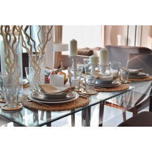 Tavola imbandita a festa con stoviglie, bicchieri e decorazioni.