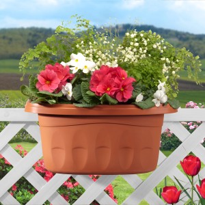 Fioriera marrone con fiori rossi e bianchi, fissata a una ringhiera bianca del balcone.
