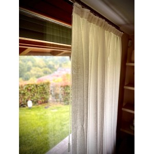 Tenda in tessuto t.b.t. chiara e trasparente davanti a una finestra con vista sul verde.