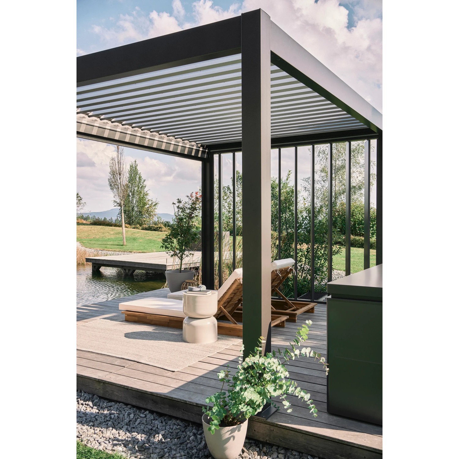 Pergola Biohort grigio scuro/argento metallizzato con tetto a lamelle e area lounge in giardino.