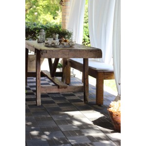 Terrazza con pavimentazione t.b.t. a scacchiera, tavolo e panca rustici.