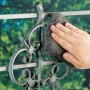 Mano che pulisce ringhiera in metallo con lana d'acciaio LUX grana 5, un abrasivo.
