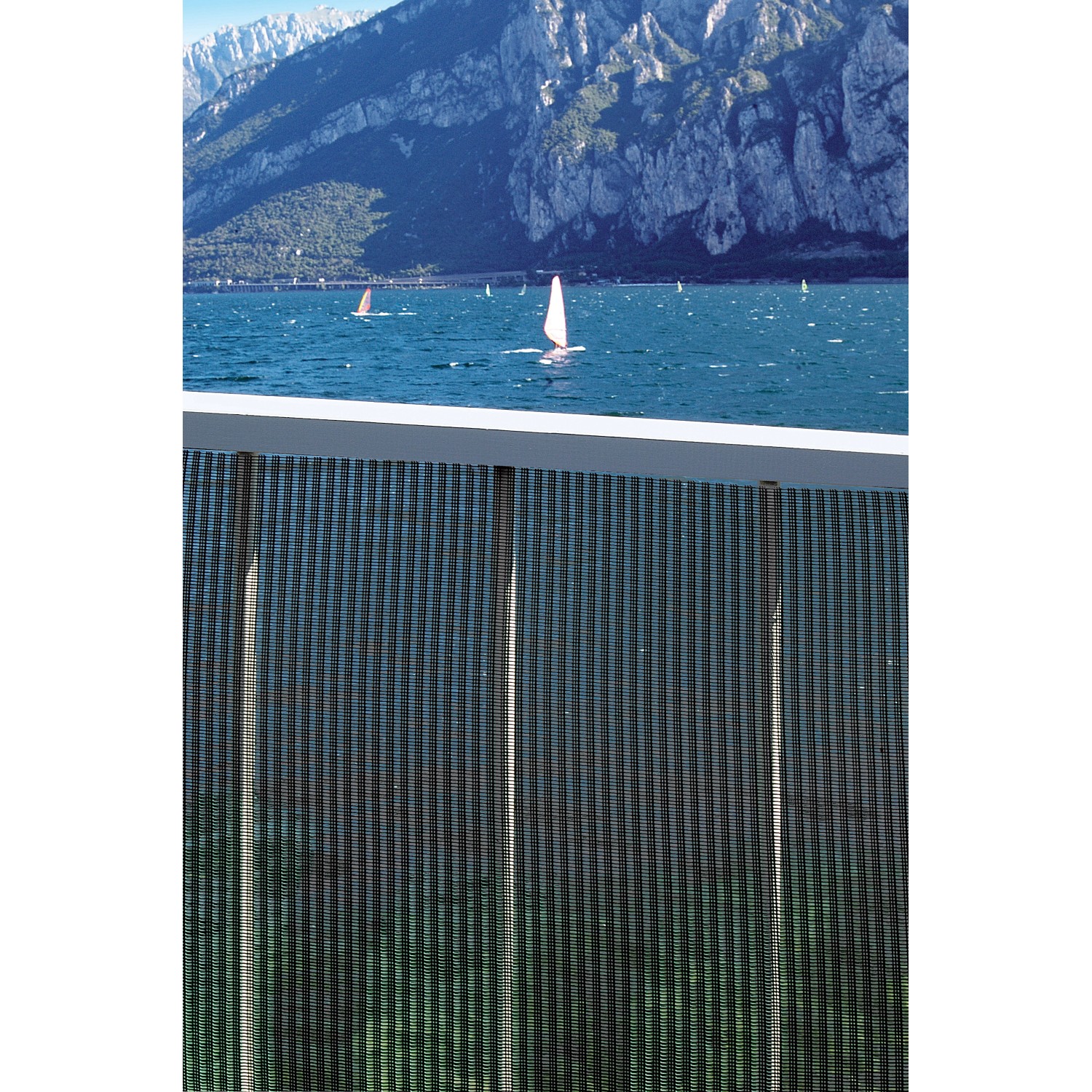 t.b.t. Frangivista davanti a panorama montano e lago con barche a vela.