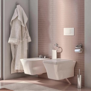 Bagno moderno con bidet, WC e accessori davanti a piastrelle rosa.