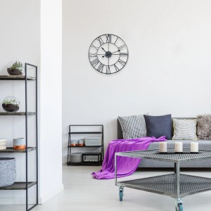 Orologio da parete in soggiorno con scaffali, divano e tavolino.