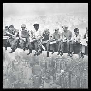 Quadri in bianco e nero: operai edili pranzano su una trave d'acciaio sopra la città.