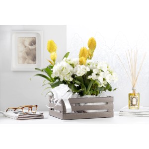 Composizione floreale in contenitore grigio con fiocco bianco, parte di una decorazione da tavolo.