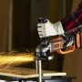Smerigliatrice angolare a batteria Black+Decker BCG720N in azione, smerigliatura con scintille.