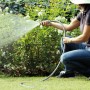 Donna che innaffia il giardino con tubo per irrigazione t.b.t.