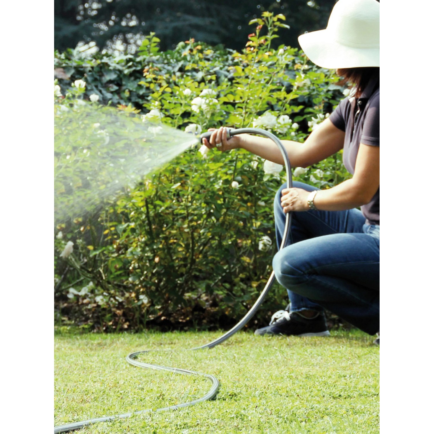 Donna che innaffia il giardino con tubo per irrigazione t.b.t.