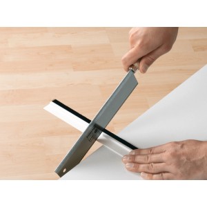 Taglio con una sega della guarnizione per porta Tesamoll Comfort bianca per pavimenti irregolari.