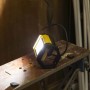 Faro LED da esterno t.b.t., giallo/nero, su un banco da lavoro.