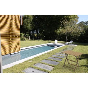 Tavolo da giardino color legno accanto alla piscina in giardino.