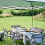 Coleman FastPitch Shelter L, verde e bianco, con tavolo e sedie in giardino.