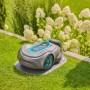 Robot tagliaerba grigio su prato davanti a ortensie bianche.