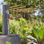 Computer per irrigazione su rubinetto con colonna in pietra e vasca di raccolta in giardino.