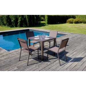 Tavolo da giardino quadrato con quattro sedie su un ponte di legno a bordo piscina.