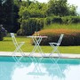 Set di mobili da giardino bianchi a bordo piscina: tavolo e due sedie. Ideale per rilassarsi all'aperto.